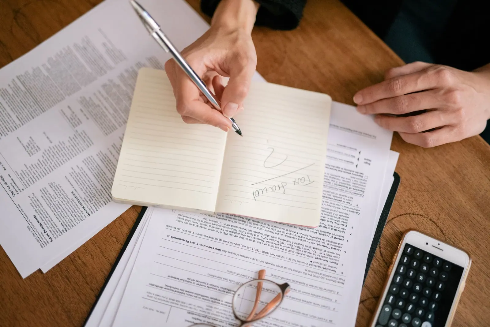 Close-up of hands writing on a notebook surrounded by tax documents and a smartphone. Canadian Content Marketing Compliance: CASL, PIPEDA and Quebec’s French Rules