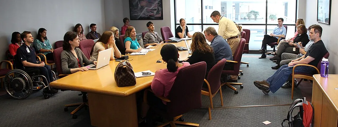 A group of colleagues takes part in a meeting around a large table.